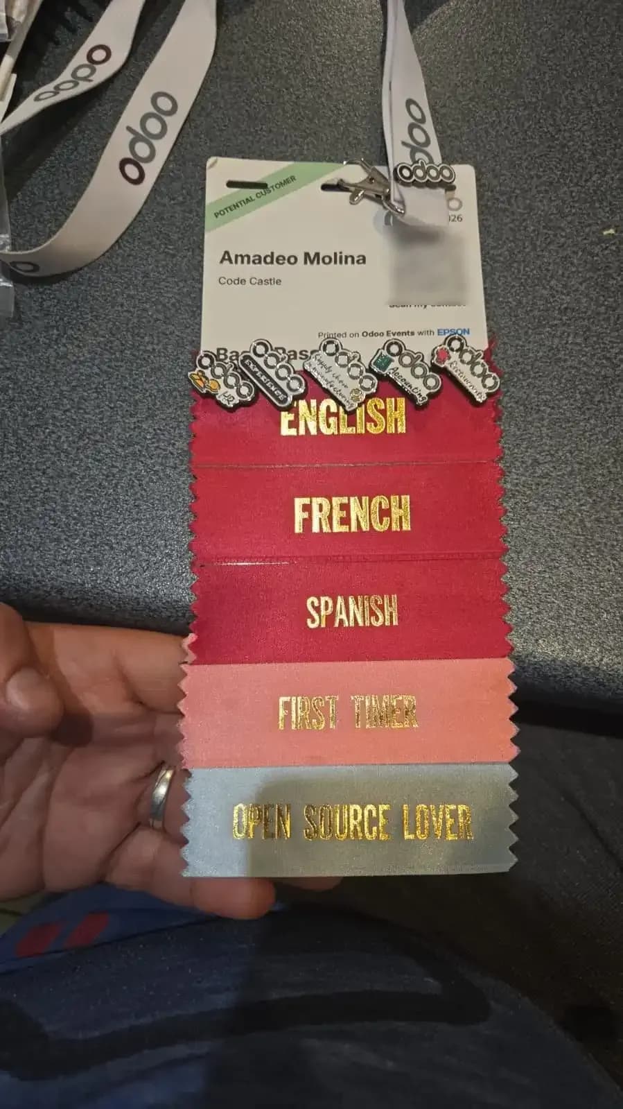 Credencial de Amadeo Molina en Odoo Experience 2026, con cintas de idiomas.